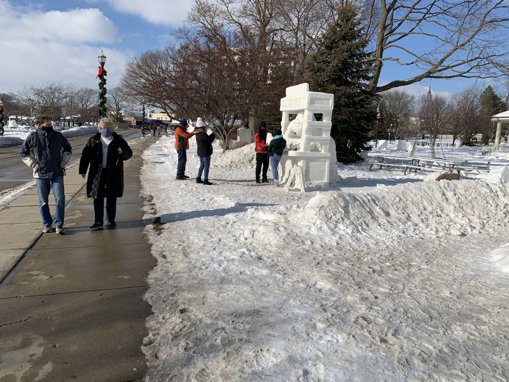 People walk along Flat Iron Park to view snow sculptures